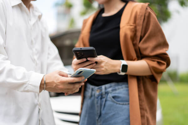 Two people stand closely while holding their smartphones